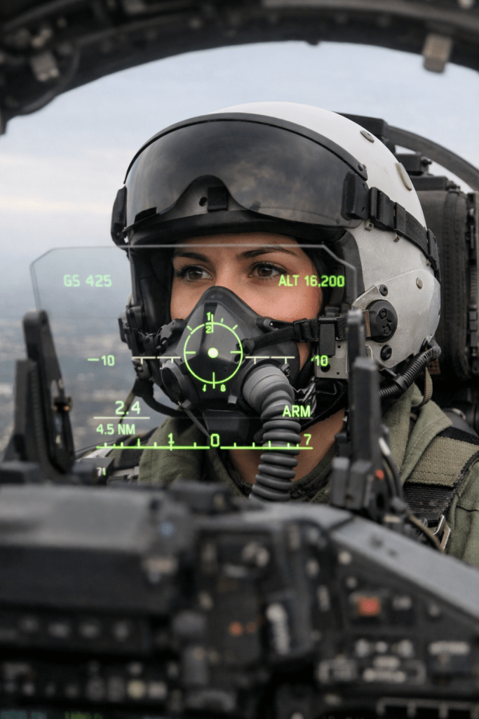 A helmeted fighter pilot in her cockpit.